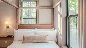 Una camera da letto con un letto, una finestra e un comodino con una lampada.
