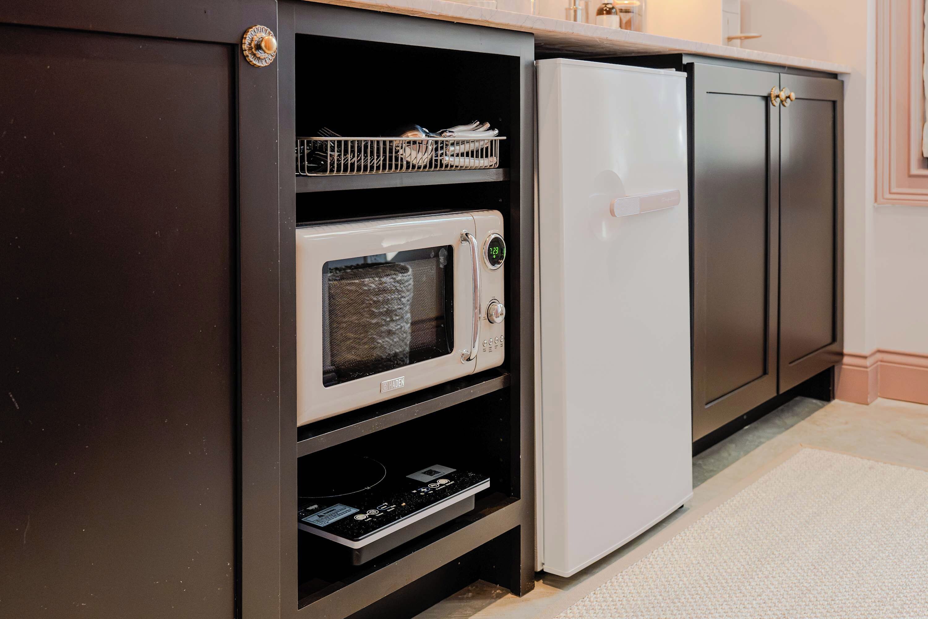 A kitchen with a built-in microwave and a refrigerator.