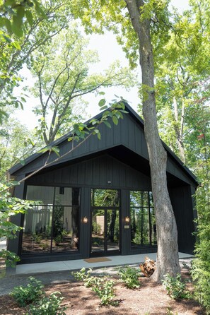 Ein modernes Haus mit großer Glasfront, umgeben von Bäumen.