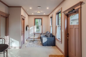 A hallway with a sofa, a table, and a door.