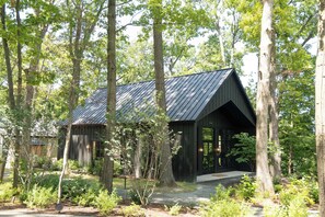 A cabin with a sloped roof surrounded by a forest.