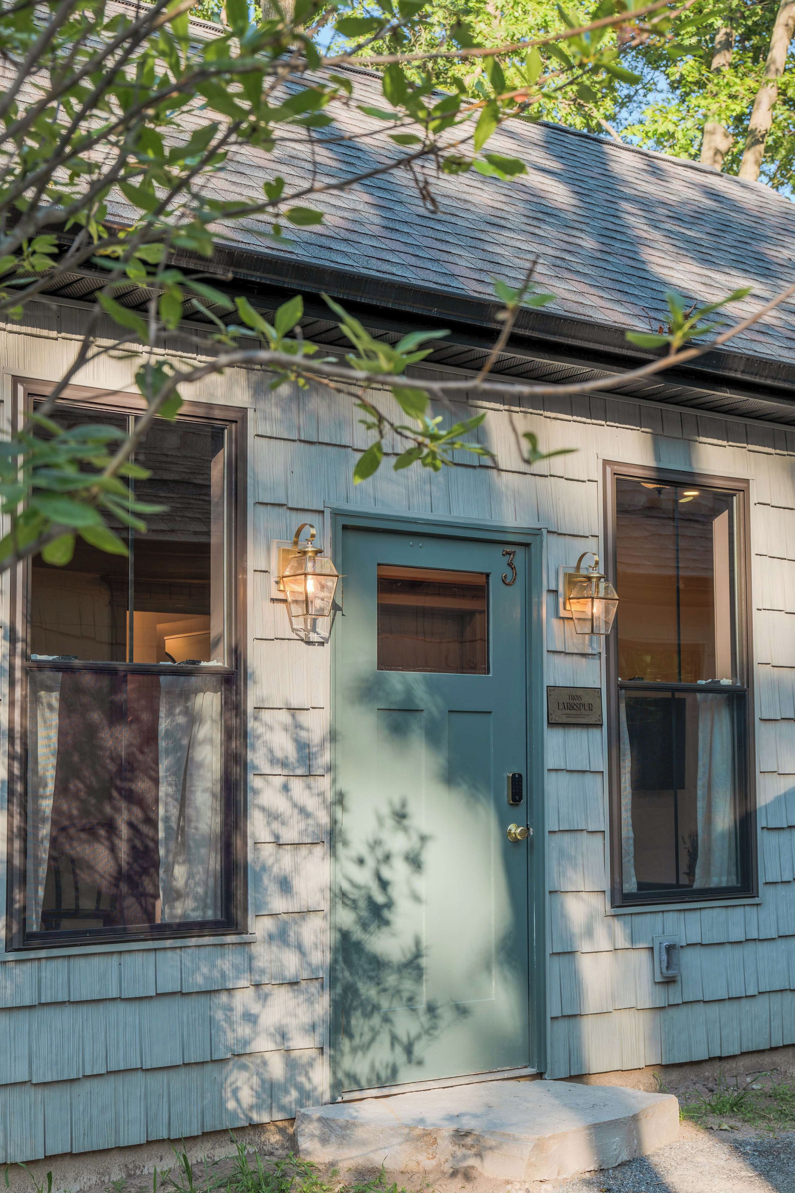 A house with a green door, two windows with lanterns, and a number '3' on the door.