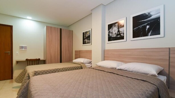 A hotel room with two beds, a desk, and a chair. There are three framed pictures on the wall. - Star Hotel (Limoeiro)
