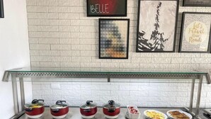A buffet setup with various dishes, a glass display case, and framed artwork on the wall. - Star Hotel (Limoeiro)