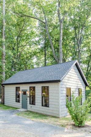 Eine kleine, eingeschossige Holzhütte mit Satteldach, umgeben von dichtem Wald.