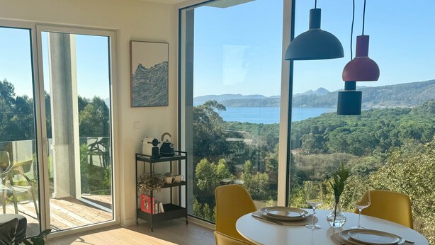 Un comedor con una mesa dispuesta para dos personas, vista a un paisaje montañoso y un amplio ventanal.