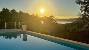 Una piscina con vistas a la puesta de sol sobre un paisaje montañoso.