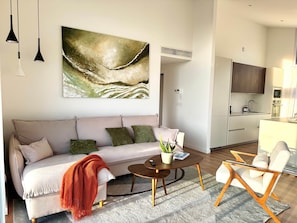 A modern living room with a sofa, coffee table, and a painting.