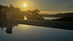 Un capvespre tranquil sobre una piscina serena amb muntanyes al fons.