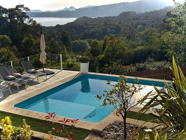 A rectangular pool with a clear view of the surrounding landscape, including trees and distant hills.