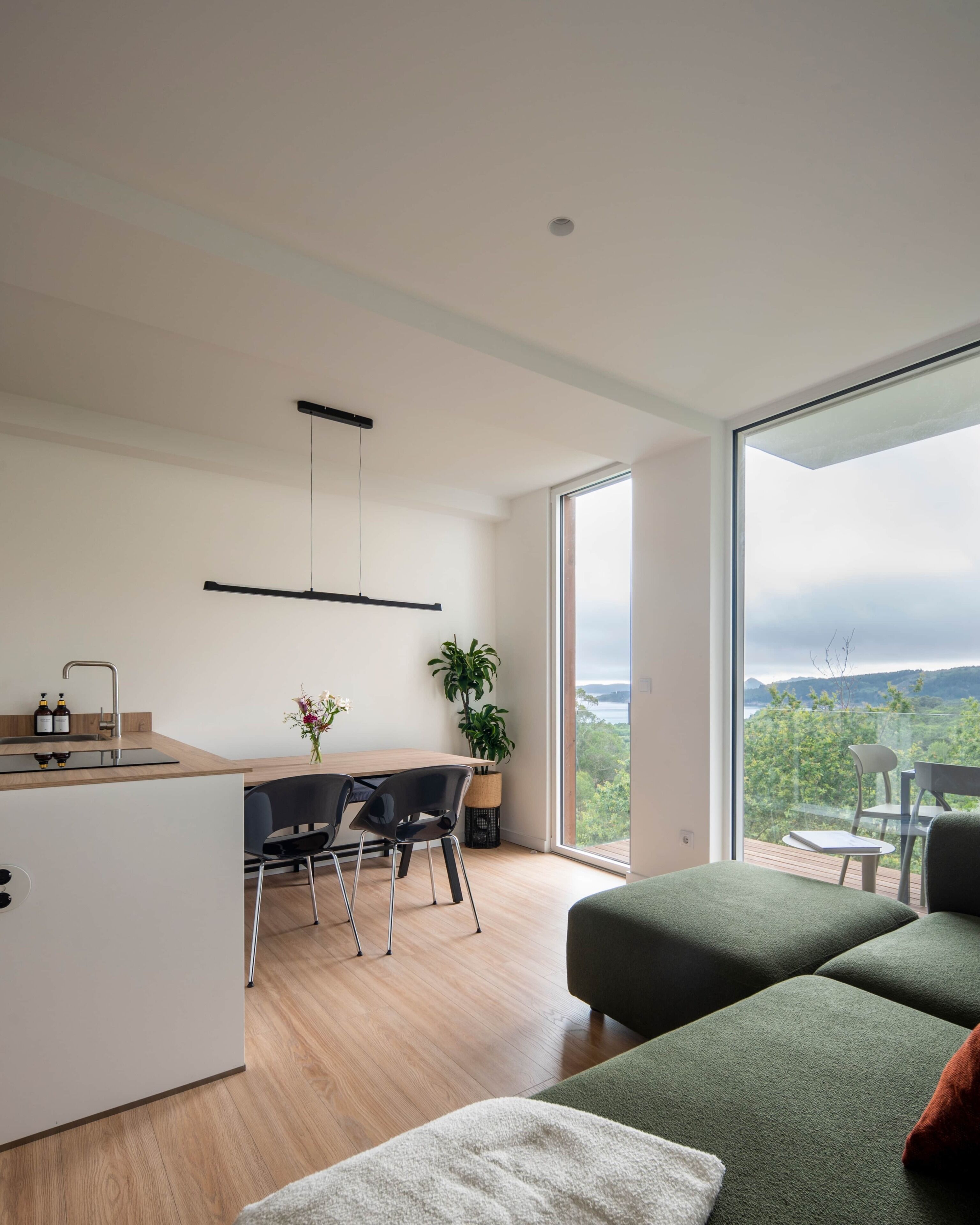 A modern kitchen with a dining area, large windows, and a view of the outdoors.