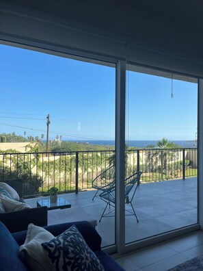 Ein Balkon mit Blick auf das Meer, einem Sessel und einer Couch.