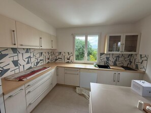 A modern kitchen with white cabinets, a patterned backsplash, a window with a view, and a sink. - 3-bedroom house, 115 m², with a garden in Saint-Malo, near Saint-Servan   (Saint-Malo)