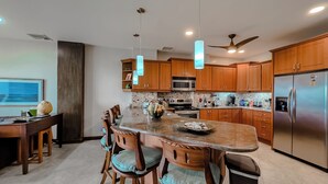 A modern kitchen with wooden cabinets, stainless steel appliances, a marble island, and pendant lighting. -  Beach front condo Jaco Tres Regalos  3 bedrooms 4th floor beautiful ocean views (Jaco)