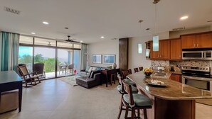 A modern kitchen with a large island, dining area, and a view of the outdoors. -  Beach front condo Jaco Tres Regalos  3 bedrooms 4th floor beautiful ocean views (Jaco)
