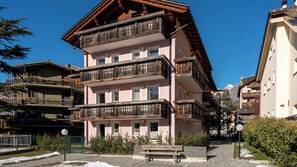 A multi-story building with balconies, a paved walkway, and snow on the ground. - Fiorini 4 - One Bedroom Apartment, Sleeps 5 (Bormio)