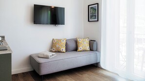 A modern living room with a grey sofa, yellow and white patterned cushions, a mounted flat-screen TV, and a framed picture on the wall. - Batèl House 4 (Como)