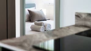 A modern hotel room with a bed, pillows, and rolled towels. - Batèl House 4 (Como)