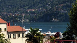 A coastal town with buildings on a hillside, a marina with boats, and a prominent water tower. - Batèl House 4 (Como)