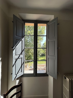 A room with a large window, a radiator, and a wooden chair. - Elegant Provençal country house with a large wooded lot and an exceptional pool   (Trets)