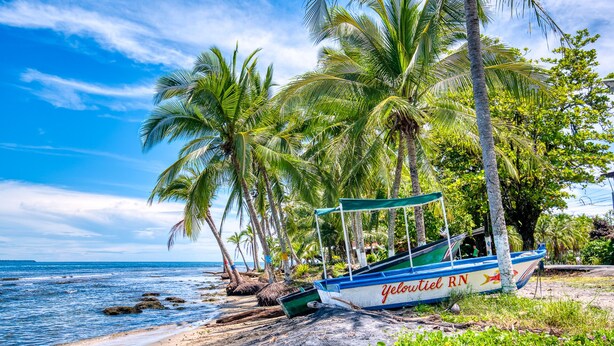 A beach with a boat named "Yeloutiel RN" and palm trees. - AroCocles Lodge (Cahuita)