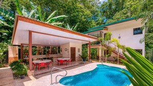 A pool area with a covered seating area, outdoor furniture, and a staircase leading to a second level. - AroCocles Lodge (Cahuita)