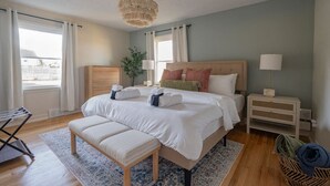 Ein Schlafzimmer mit einem großen Bett, Nachttischen, einer Bank und Blick ins Freie.