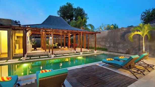 Un espace aménagé au bord de la piscine, avec des chaises longues et un coin salon abrité.