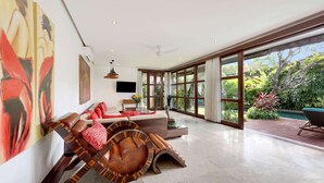 Un salon spacieux, doté d’un canapé moderne, d’une table basse en bois originale et d’une grande fenêtre donnant sur le jardin.