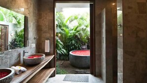 Une salle de bain moderne avec un lavabo en pierre, un miroir et un espace douche.
