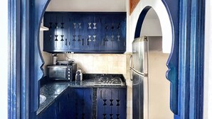 Una cocina con gabinetes azules, estufa, microondas y refrigerador.
