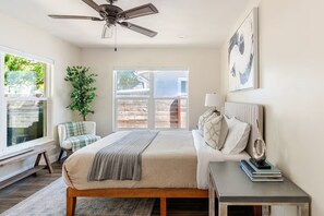Ein Schlafzimmer mit Bett, Nachttisch, Lampe und Deckenventilator.