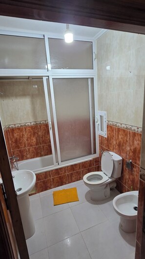 Ein Badezimmer mit einer Badewanne, zwei Toiletten, einem Waschbecken und einer Duschkabine.