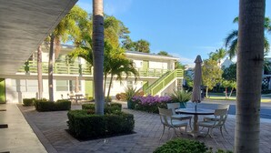 A covered outdoor area with a table and chairs, surrounded by palm trees and greenery. - Just Listed:  Cozy 1-bedroom condo in fabulous Olde Naples near downtown (Naples)