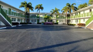 A two-story motel with a central courtyard, green railings, and palm trees. - Just Listed:  Cozy 1-bedroom condo in fabulous Olde Naples near downtown (Naples)