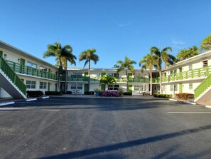 Ein zweistöckiges Motel mit Innenhof, grünen Geländern und Palmen.