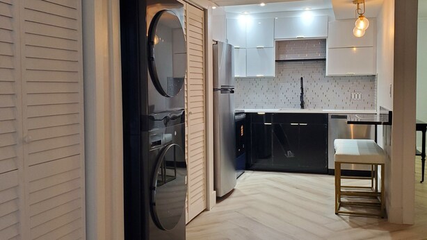 A modern kitchen with white cabinets, a stainless steel refrigerator, and a wooden floor. - Just Listed:  Cozy 1-bedroom condo in fabulous Olde Naples near downtown (Naples)