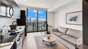 Eine moderne Küche mit Herd, Spüle und einem großen Fenster mit Blick auf eine Stadtlandschaft.
