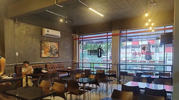 A restaurant interior with tables and chairs, a large window with a view, and a sign reading "RSVONOP". - Smart Malls (Belém)