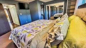 Un dormitorio con cama, ventilador de techo, espejo y armario.
