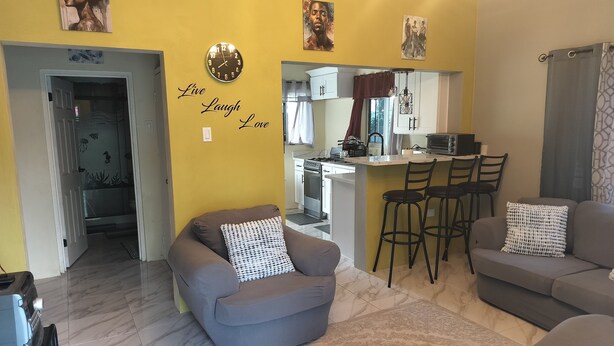 Een woonkamer met twee banken, een salontafel en een zichtbare keuken door een open deur.