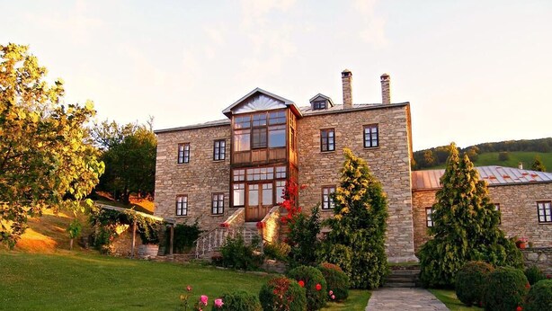 A stone building with a central staircase, a stone pathway, and well-maintained gardens with pink flowers. - La Moara (Amyntaio)