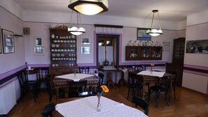 A dining area with wooden tables, chairs, and a central vase with flowers. - La Moara (Amyntaio)