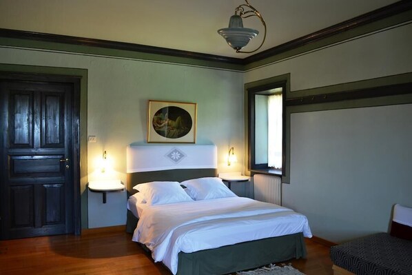 A bedroom with a bed, bedside lamps, a painting, a window, and a door. - La Moara (Amyntaio)