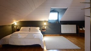 A bedroom with a bed, two bedside lamps, a window, a radiator, and a wooden floor. - La Moara (Amyntaio)