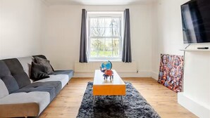 Ett modernt vardagsrum med en soffa, ett soffbord, en jordglob och en tv.