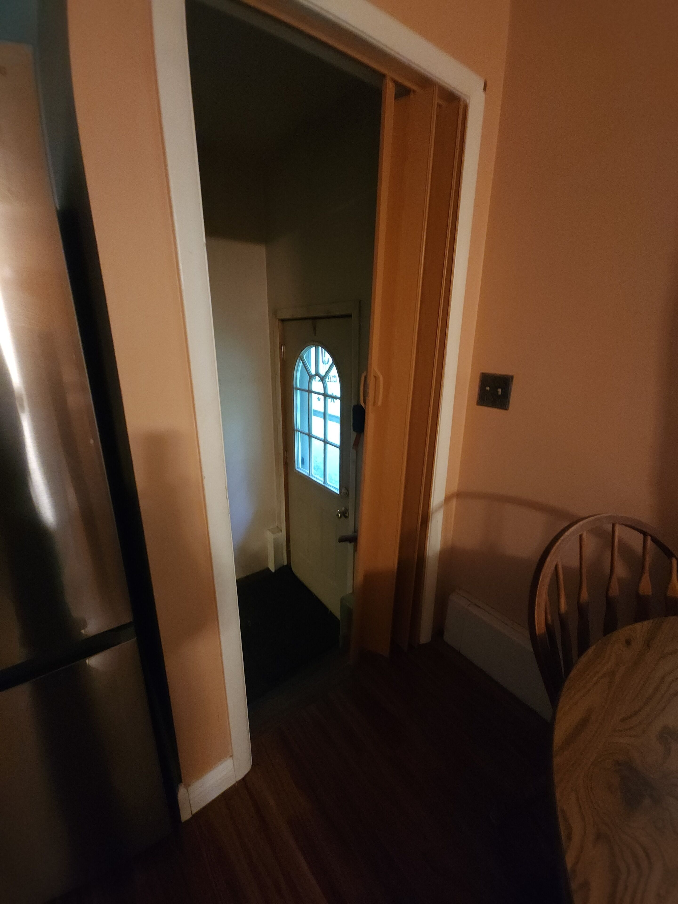 Un couloir avec une porte en bois qui donne sur une pièce dotée d’une fenêtre.