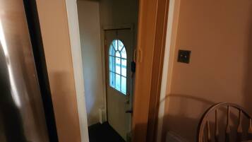 Un couloir avec une porte en bois qui donne sur une pièce dotée d’une fenêtre.