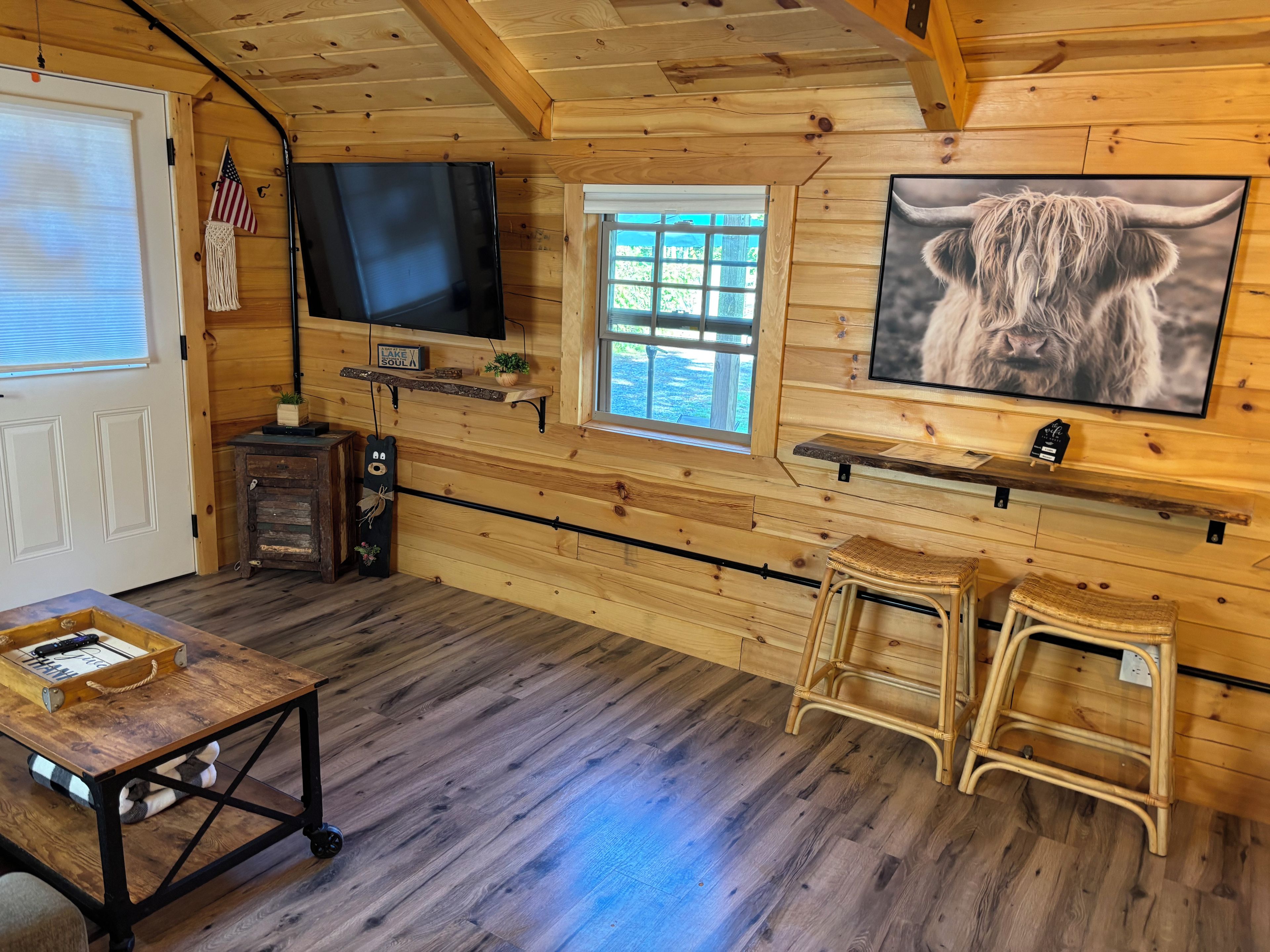 A cabin interior with a television, wooden walls, a window, and a high chair.