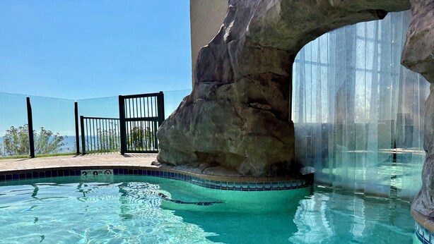Una piscina cristalina con una formación rocosa y una barrera de vidrio.